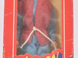 La poupée qui se trouve dans la boîte porte une veste rouge et un pantalon bleu.