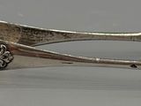 a silver spoon with a flower on it and a clock on it