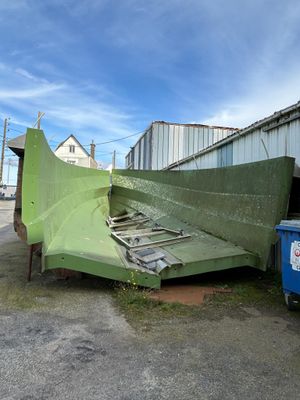un avion vert posé au sol à côté d'une poubelle bleue