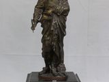 statue en bronze représentant un homme tenant une horloge, posée sur un socle en marbre