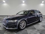 Une Audi noire est garée dans une grande pièce au sol carrelé.