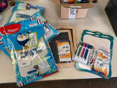 une boîte contenant des stylos, des feutres et des marqueurs, ainsi qu'un sac rempli de marqueurs, posés sur une table