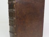 an old brown book sitting on top of a table next to a white wall