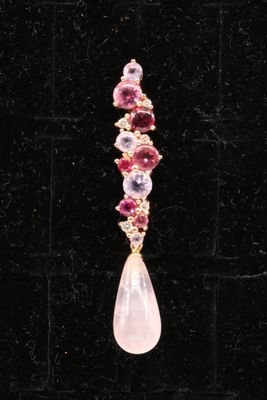 a close up of a pair of pink and purple earrings on a black surface