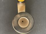 a yellow handle on a metal object on a gray surface