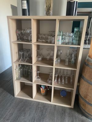 des bouteilles et des verres posés sur une étagère dans une pièce où se trouve un tonneau de vin