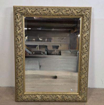 une image représentant un miroir à cadre doré posé sur un parquet