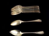 Plusieurs cuillères et fourchettes sont disposées en rangée sur une surface noire