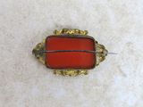 an image of a red glass broochle with gold trim
