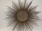 a mirror on the wall that has a sunburst on it
