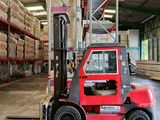 a red fork truck parked in a warehouse with stacks of wood