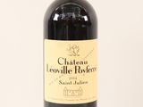 the bottle of red wine is sitting on a white surface