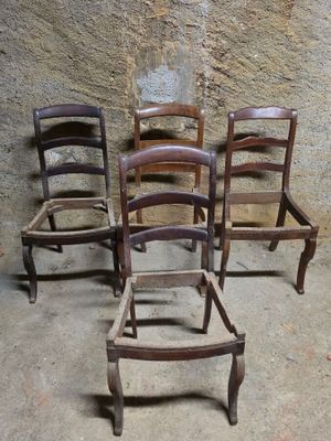 quatre chaises en bois sont alignées en rang contre un mur de pierre