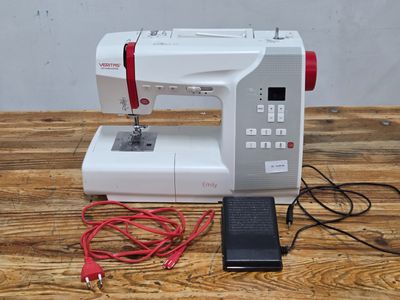 a white sewing machine on a wooden table with a red cord
