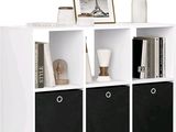 une bibliothèque blanche avec des bacs noirs et un vase rempli de fleurs