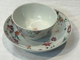 a bowl and saucer on a table with a white table cloth