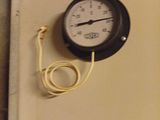 a thermometer on the wall next to a cord