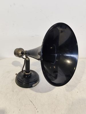 une enceinte rétro noire et argentée posée sur une surface blanche