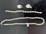 un collier de perles et des boucles d'oreilles ornées de breloques en forme de dés, exposés dans une vitrine