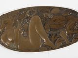 une plaque en bronze représentant une femme, posée sur un fond blanc