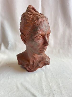 une sculpture en argile représentant la tête d'une femme sur fond blanc