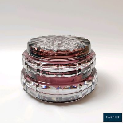 un récipient en verre muni d'un couvercle rose, posé sur une surface blanche