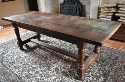 une grande table en bois posée sur un tapis devant une cheminée