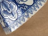 someone is holding a blue and white vase with a design on it