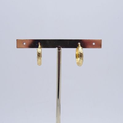 une paire de boucles d'oreilles plaquées or posées sur un présentoir en métal