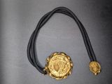 a close up of a necklace with a gold medallion on it