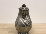 a silver vase sitting on a wooden table