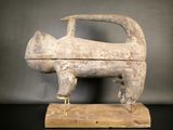 sculpture représentant un chien, posée sur un socle en bois, sur une surface noire