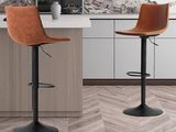 Deux tabourets de bar en cuir marron sont disposés devant le comptoir de la cuisine.