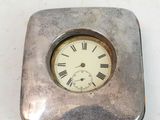 a small silver clock with roman numerals on it