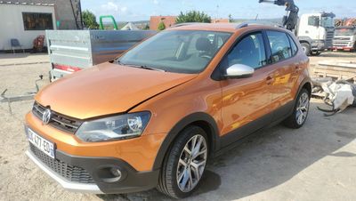 an orange vw cross parked in a parking lot next to a trailer