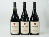 three bottles of wine are lined up on a white surface