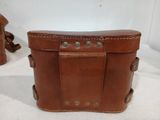 two brown leather bags sitting next to each other on a white surface
