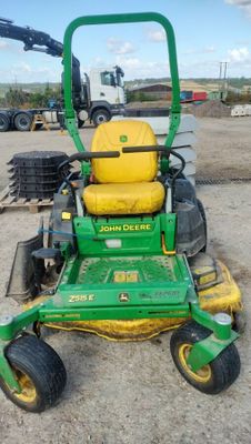 a picture of a green and yellow lawn mower parked in a lot