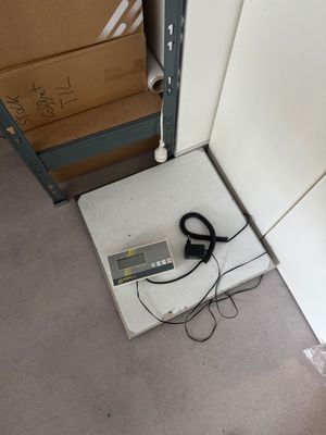 a scale that is sitting on the floor next to a stack of boxes