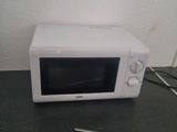 a white microwave sitting on a counter with a pair of scissors