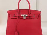 un sac à main en cuir rouge posé sur une table blanche