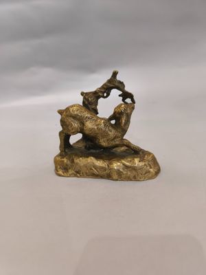 une statue en or représentant une chèvre et un oiseau posés sur un rocher
