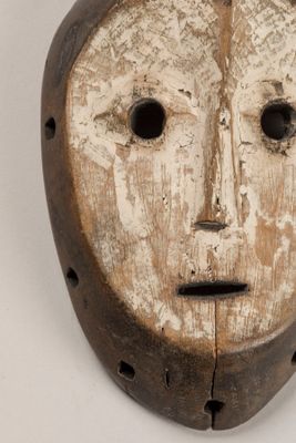 un vieux masque en bois percé de trous au milieu du visage