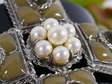 a close up of a brooch with pearls on it
