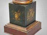 a green and gold vase on a wooden base