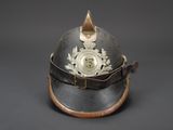 an old helmet with a gold emblem on it on a black background