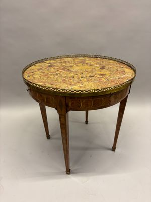 une petite table ronde dont le plateau est orné d'un motif jaune et marron