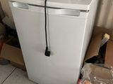 a white refrigerator with a bottle of water on top of it