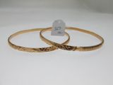 deux bracelets rigides en or ornés de motifs gravés et accompagnés d'une étiquette de prix