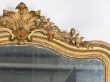 a mirror with a gold frame on a white wall